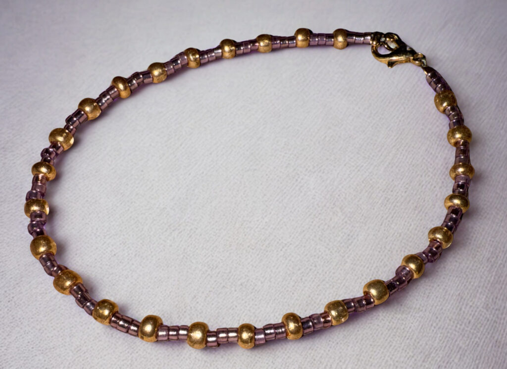 Large bracelet or anklet made of alternating purple and gold beads with a gold lobster claw clasp.