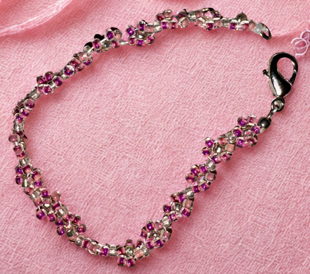 Small pink bracelet made with pink flower beads and a lobster claw clasp.