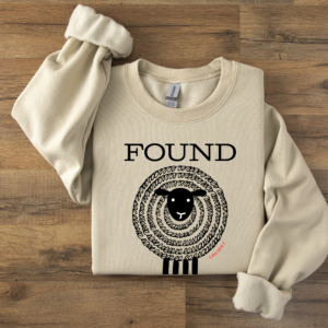 Sweatshirt folded on a table with the word FOUND over a black sheep