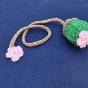 Crochet bookmark, bright green cactus with pink flower on top. Light brown string with additional pink flower on bottom.