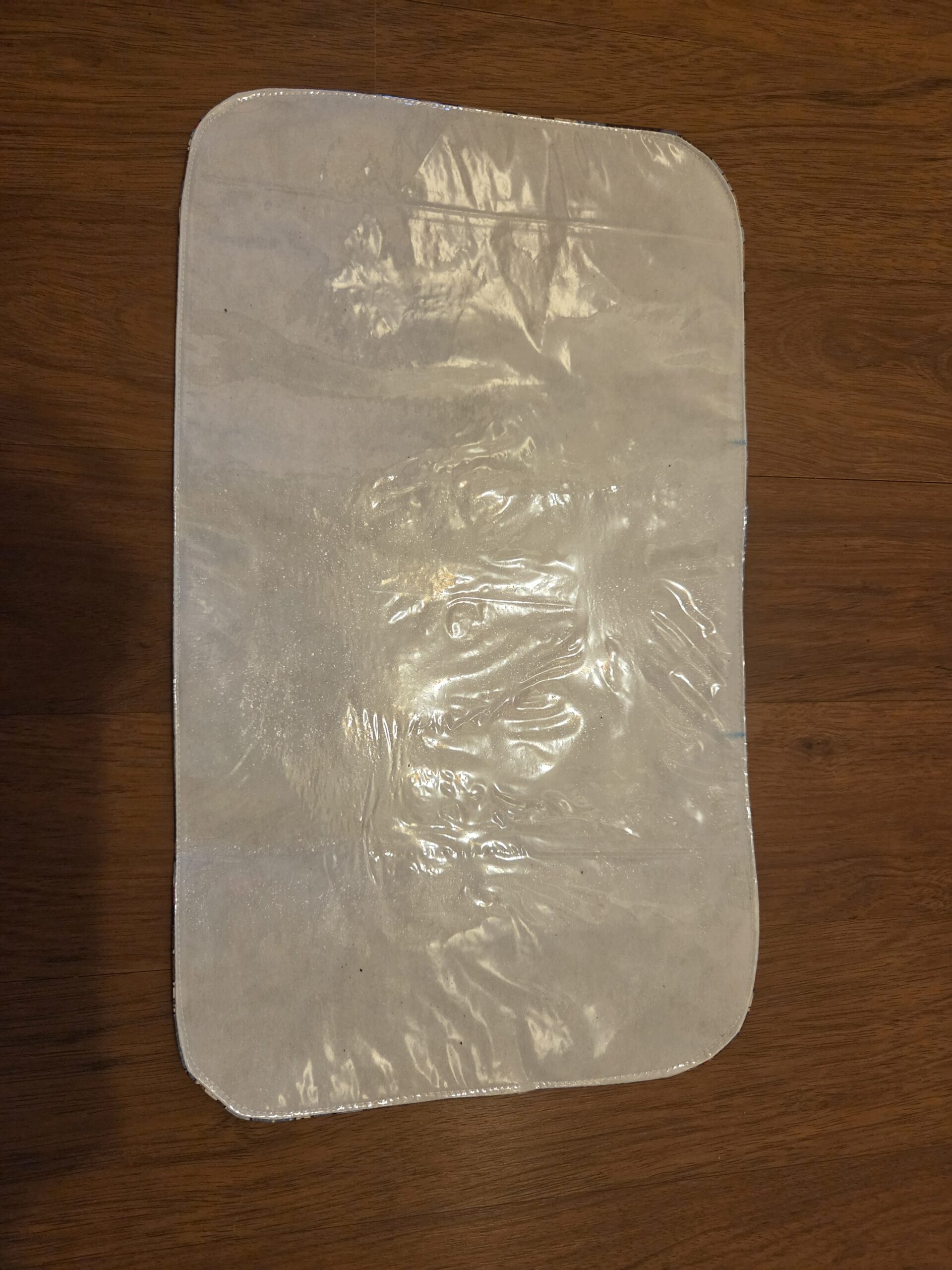 Small pet bowl mat featuring adorable doggie print in blue & brown. Plastic back.