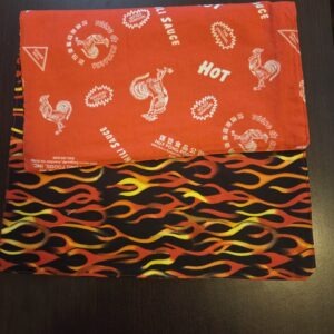 Reversible placemats, set of 4. Top side features red, yellow, and orange flames on black; bottom features Sriracha hot chili sauce print.