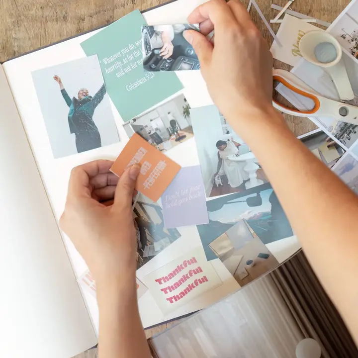 Hands placing cut out images into vision board journal