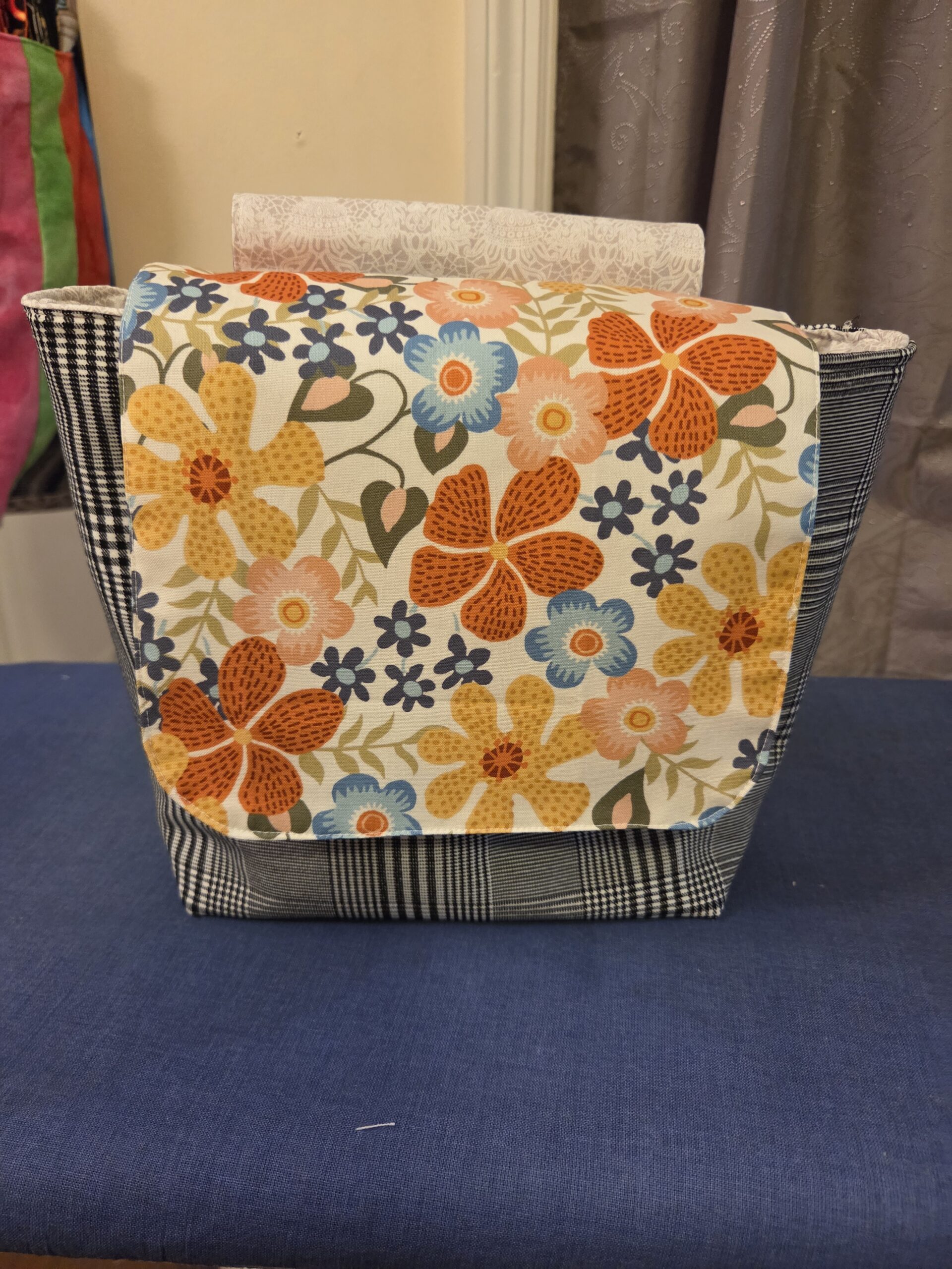 Hanging Messenger Bag in black and white plaid with retro floral accent. Metal snap closure. Zippered pocket.