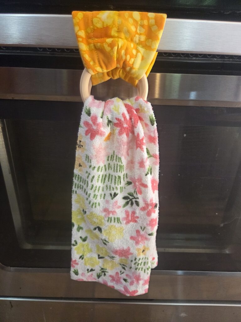Towel hanger turns any kitchen towel into a hanging towel for the stove, dishwasher, or drawer handles.