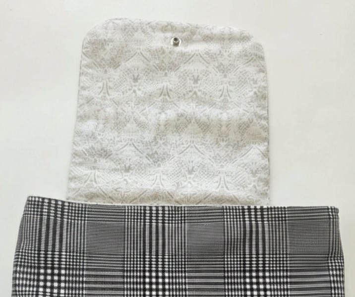 Messenger bag pictured with front flap open, exposing the gentle design on the lining fabric. Neutral colors, light gray on white.