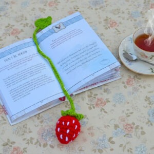 Strawberry bookmark, hand crocheted, bright red strawberry with tiny white "seed" details. Grass-green stem and leaf at the end of the bookmark.