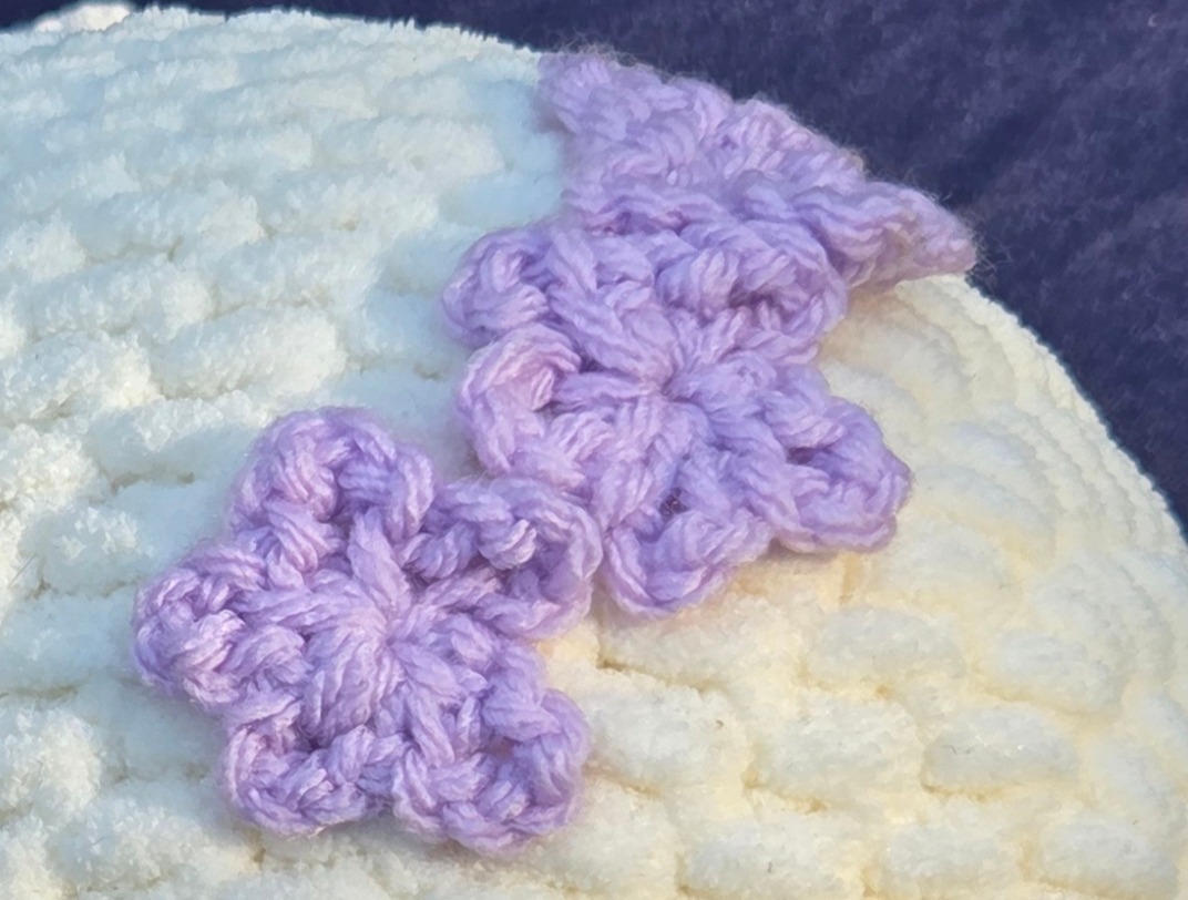 Echo the Whale, hand crocheted white whale plushie, featuring a light purple hair bow and black safety eyes.
