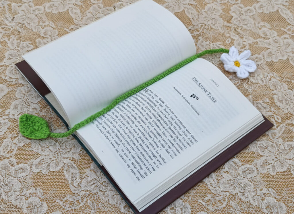 Crocheted bookmark, white daisy with delicate yellow center, pretty green stem & leaf on the end.