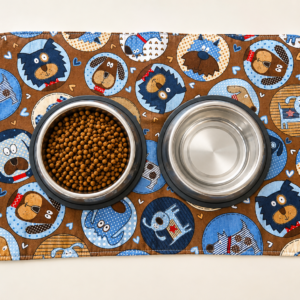 Dog food and water bowls on mat. Mat features adorable print of several breeds of dogs.