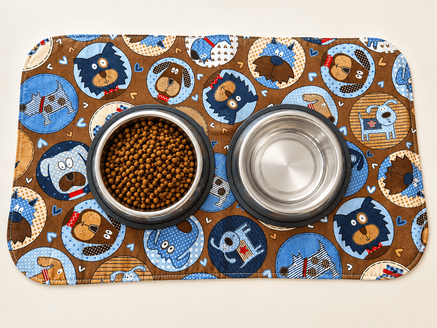 Dog food and water bowls on mat. Mat features adorable print of several breeds of dogs.