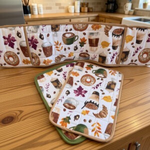 Set of 3: 2 casserole size hotpads and one double oven mitt. Features fall fabric with colorful autumn leaves in red and gold, plus goodies including coffee, donuts, and pastries. Offwhite fabric background, trimmed in matching beige and green.